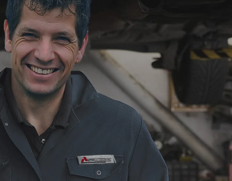 Monteur van Autobedrijf Kees onder een auto op de brug